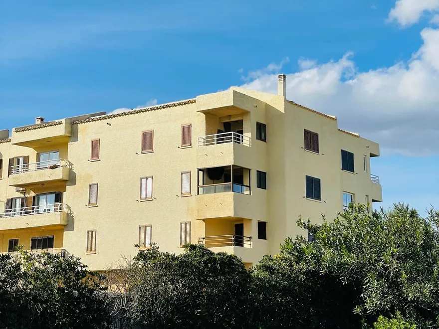 Immeuble méditerranéen aux façades ocre avec balcons, sous un ciel bleu
