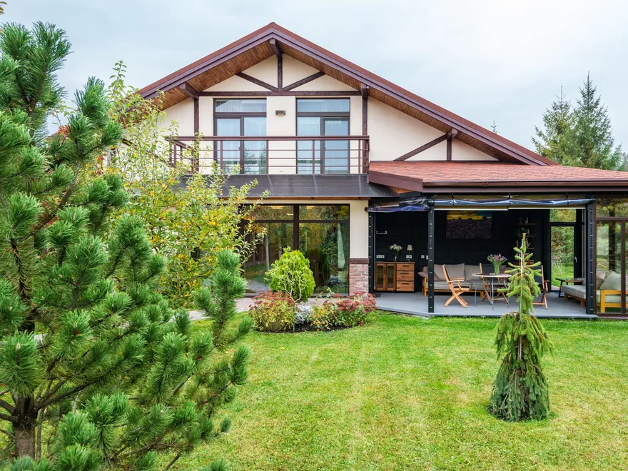 Maison à pignon bois avec véranda vitrée ouverte sur un grand jardin