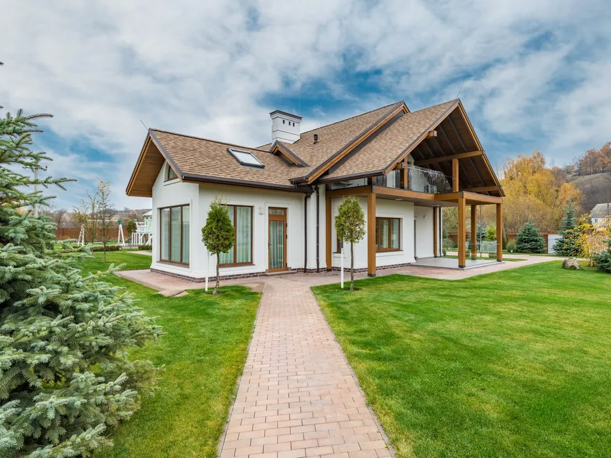 Maison contemporaine à toiture bois entourée d'une pelouse et d'une allée pavée